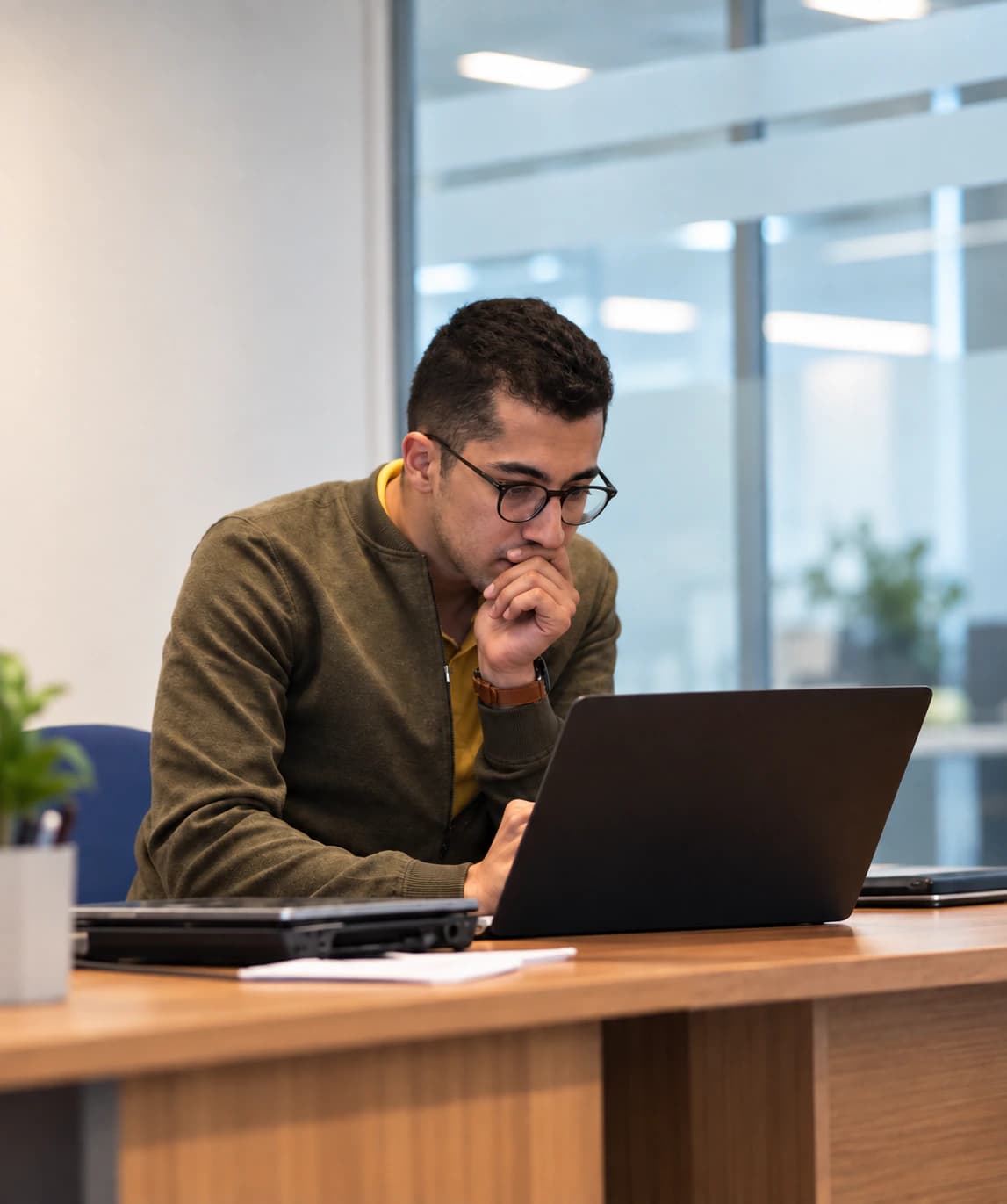 Abdessamad Tirhzaoui travaillant à son ordinateur portable dans un bureau vitré.
